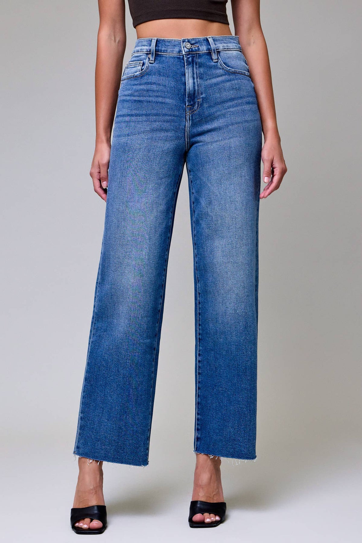 Person wearing blue jeans on a plain background