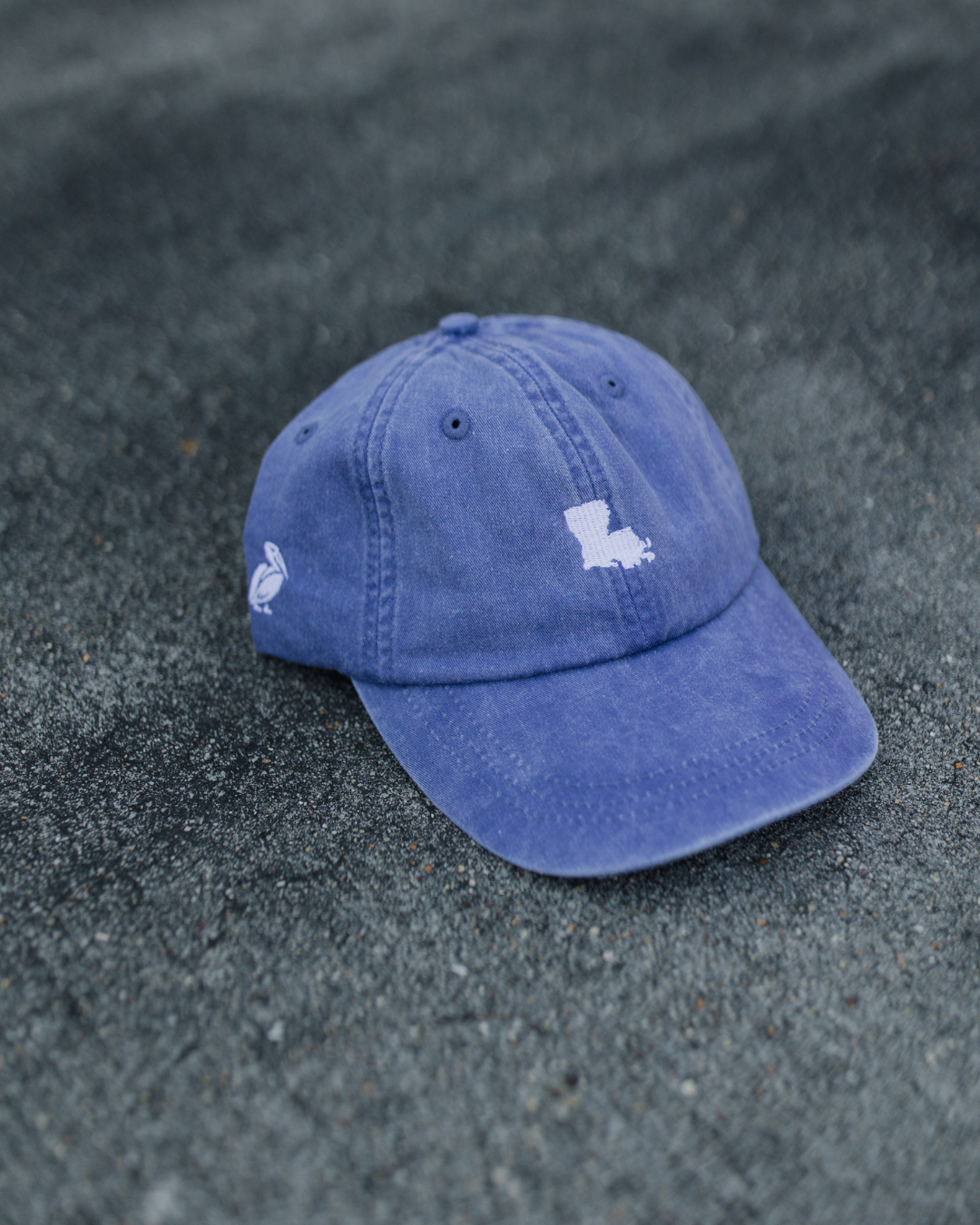 Blue cap with white logos on a sandy surface