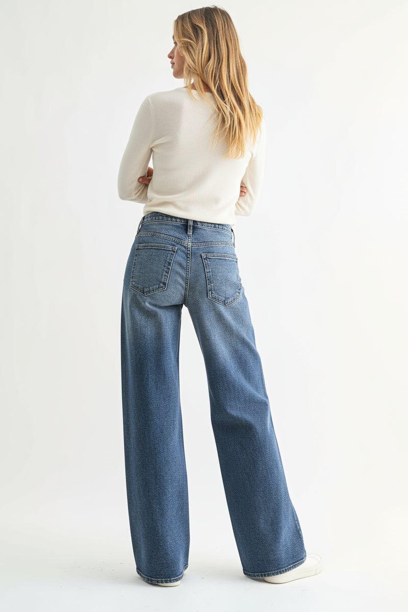 Woman wearing a gray argyle sweater and blue jeans on a white background