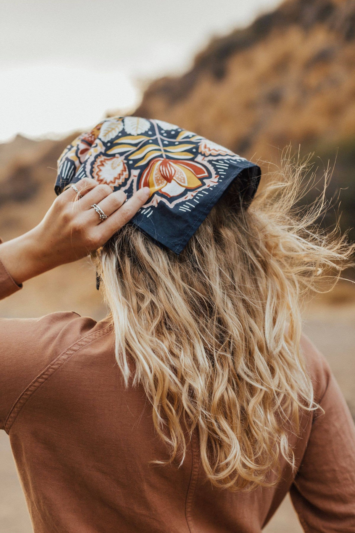 Person wearing a colorful headscarf with a blurred natural background