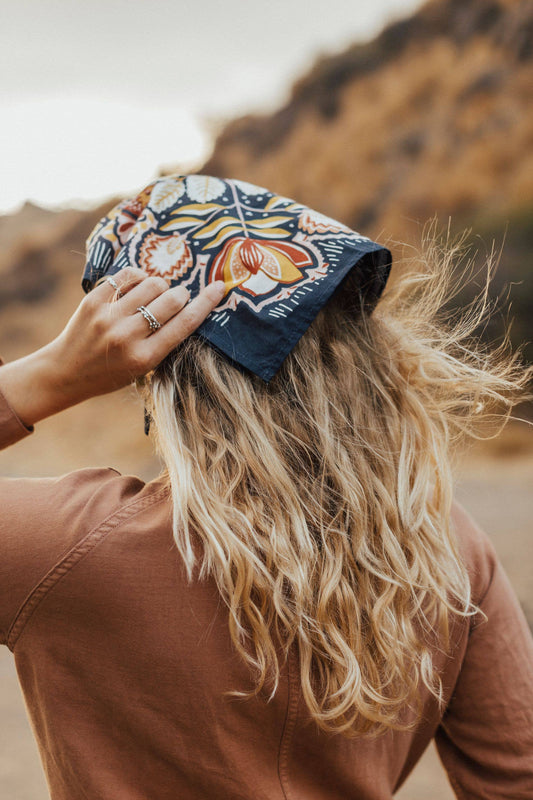 Person wearing a colorful headscarf with a blurred natural background