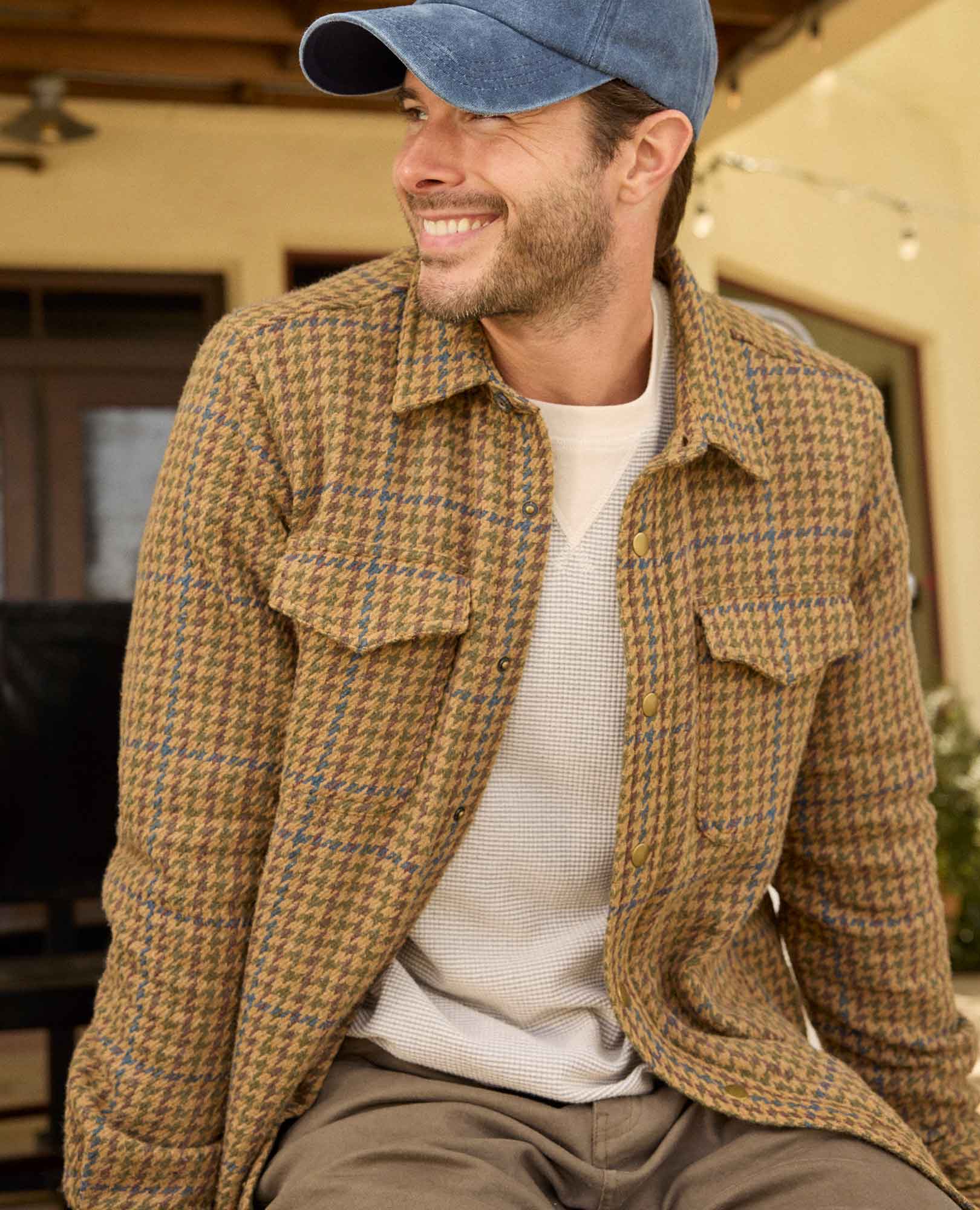 Man wearing a brown checkered jacket and blue cap outdoors