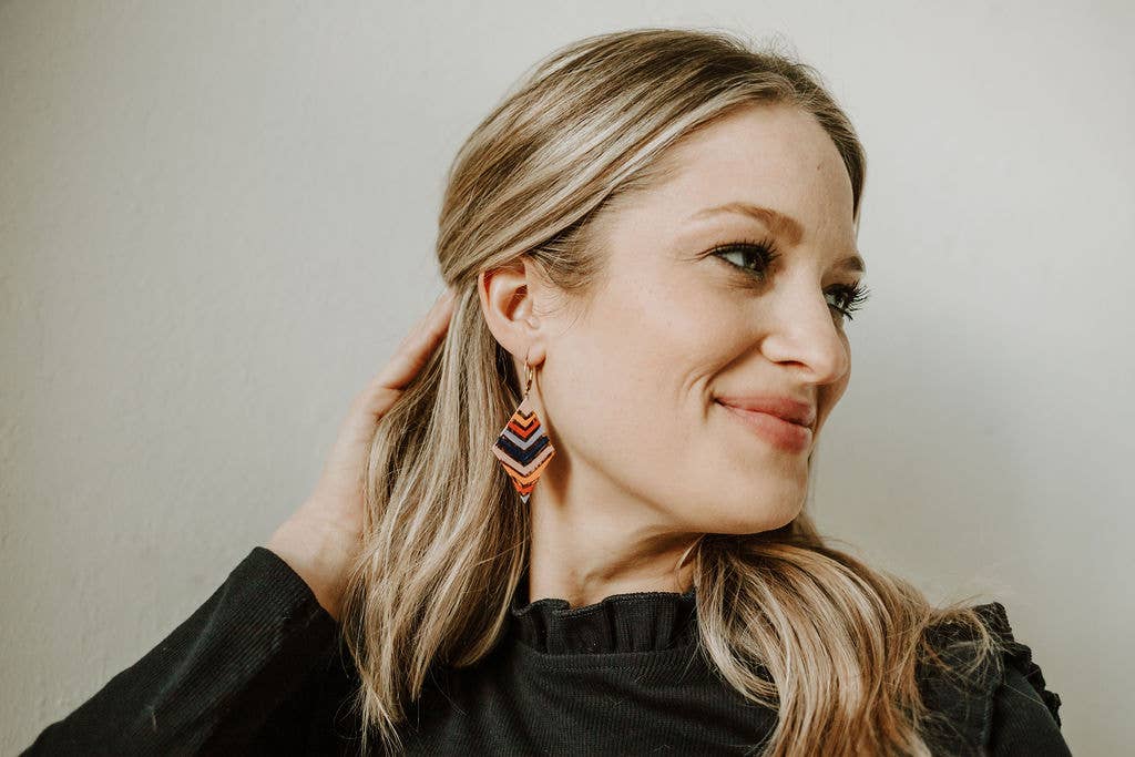 Woman wearing colorful earrings against a neutral background