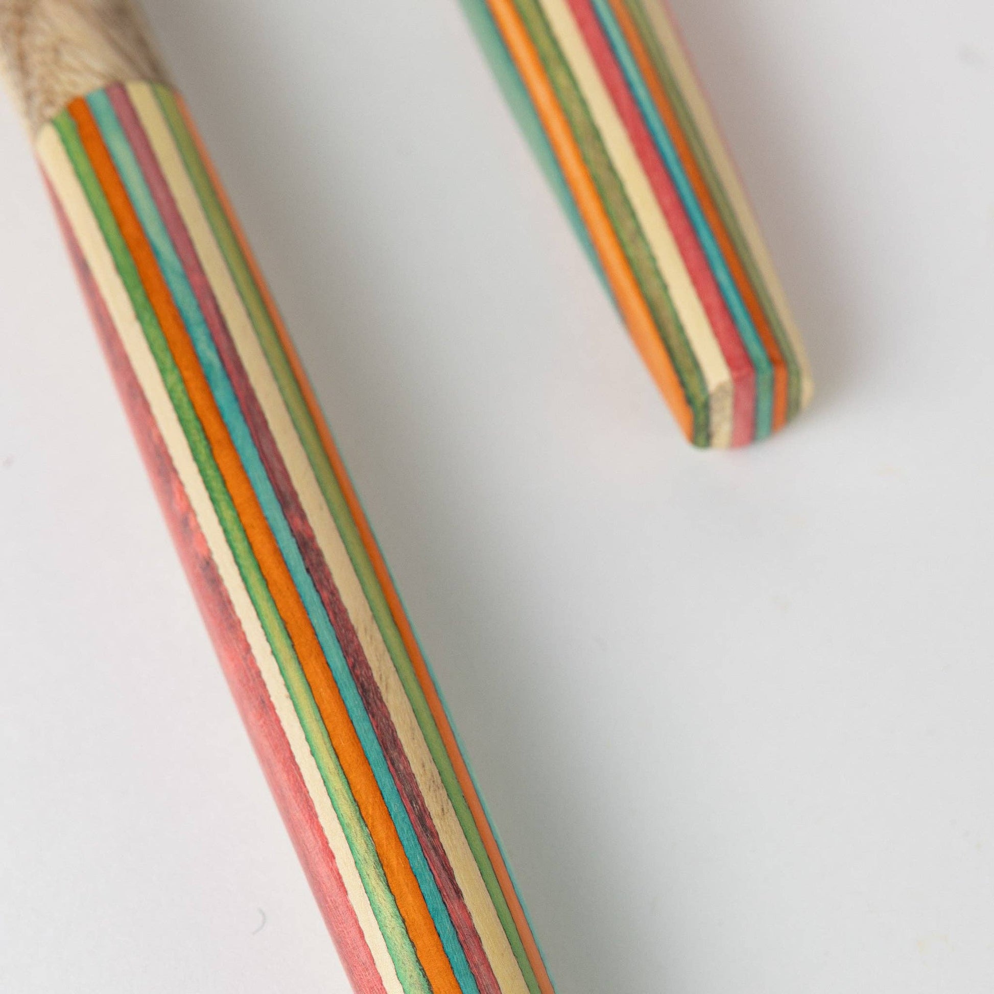 Two wooden pencils with multicolored striped designs on a white background