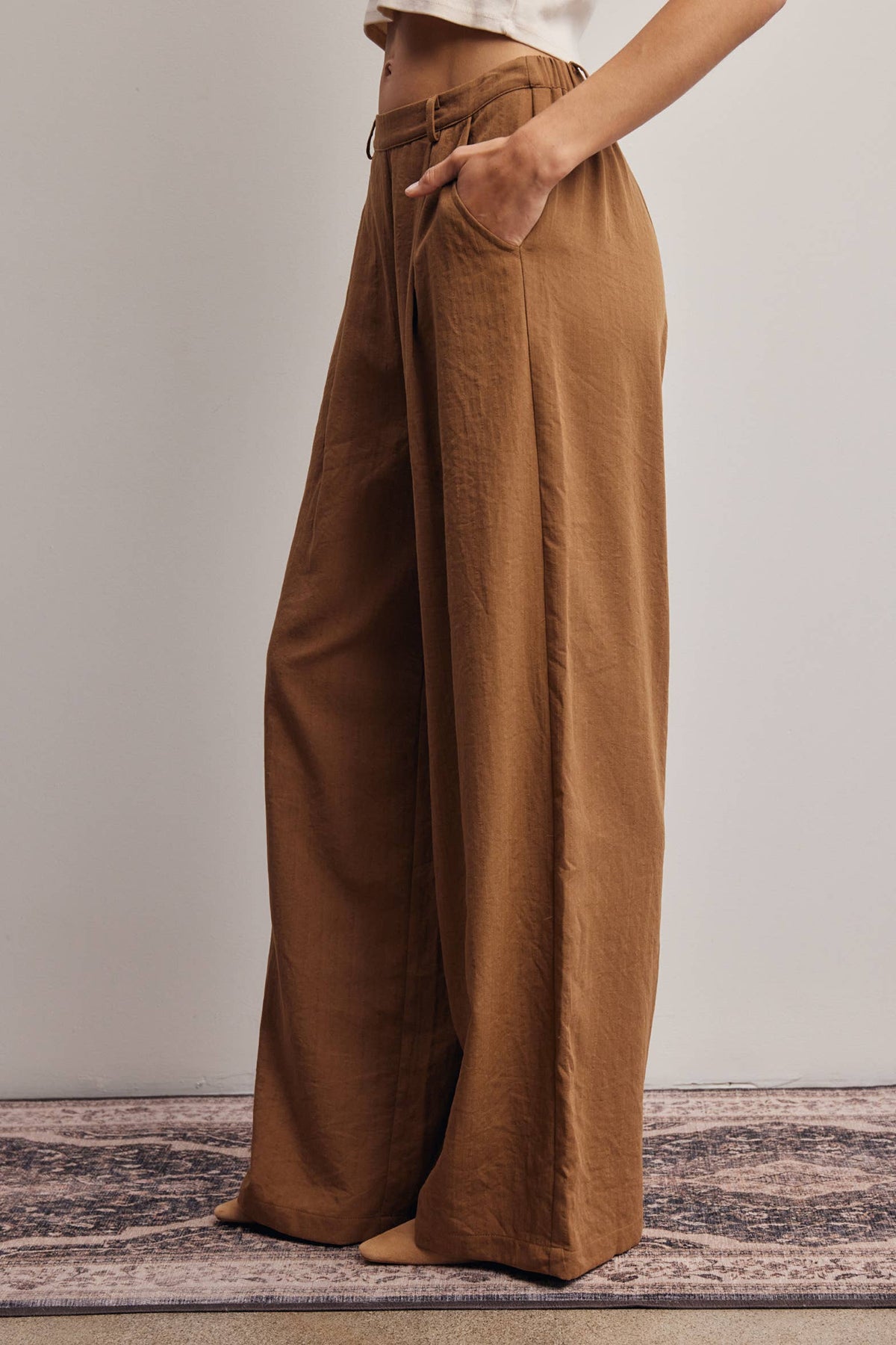 Brown wide-leg pants worn by a person on a neutral background