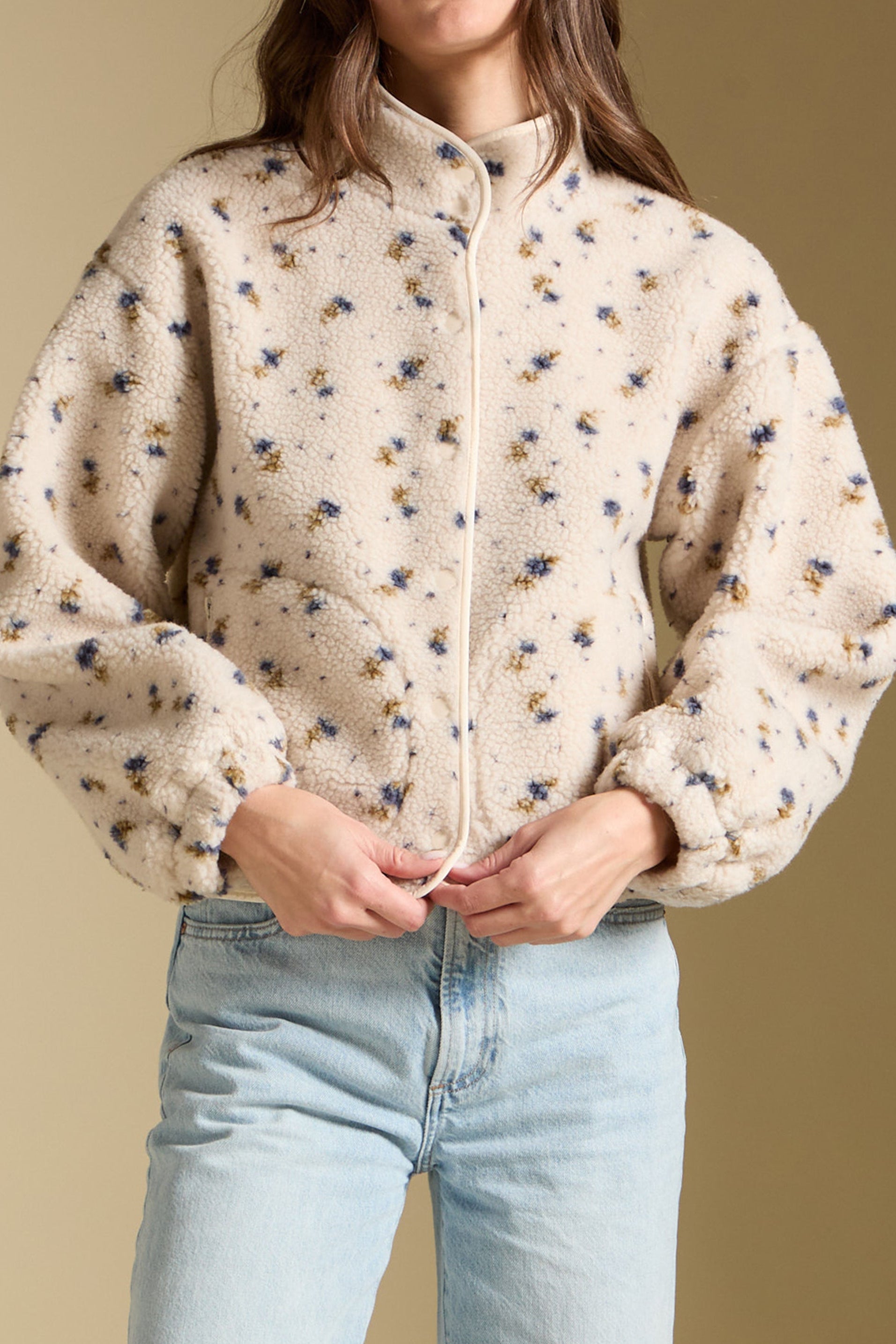 Woman wearing a floral patterned jacket against a beige background