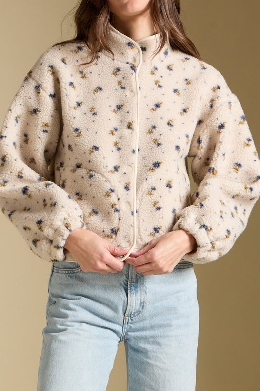 Woman wearing a floral patterned jacket against a beige background
