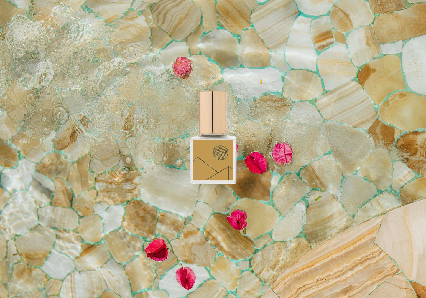 Perfume bottle with pink flowers on a mosaic stone background