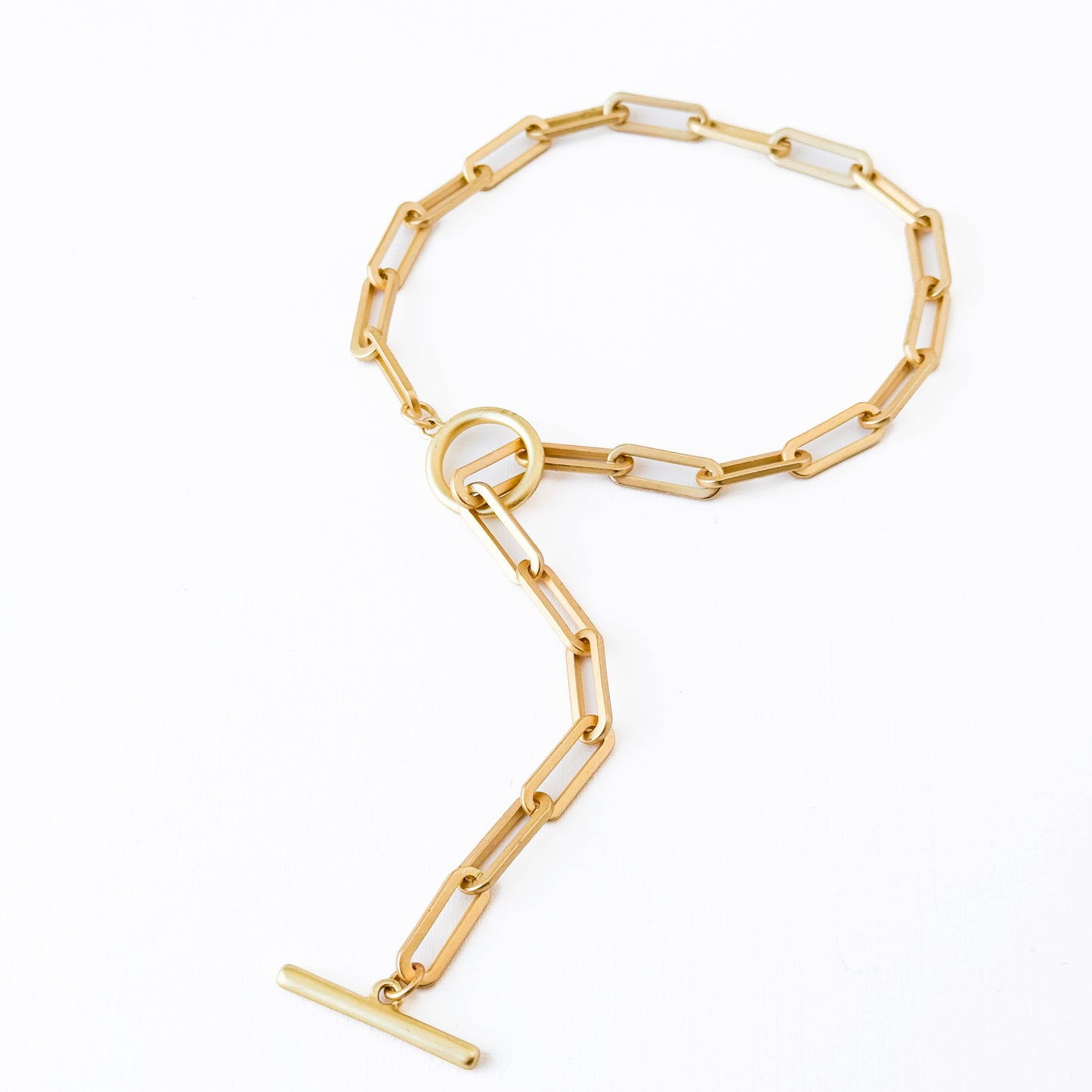 Gold chain bracelet with a white stone on a white background
