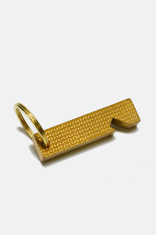 A gold-colored textured metal keychain tool with a split ring, shown on a clean white background.