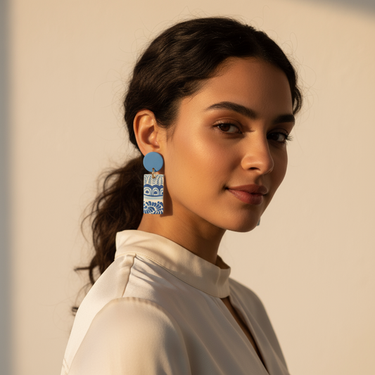 A pair of blue and white patterned earrings made from buffalo horn, displayed against a white background.