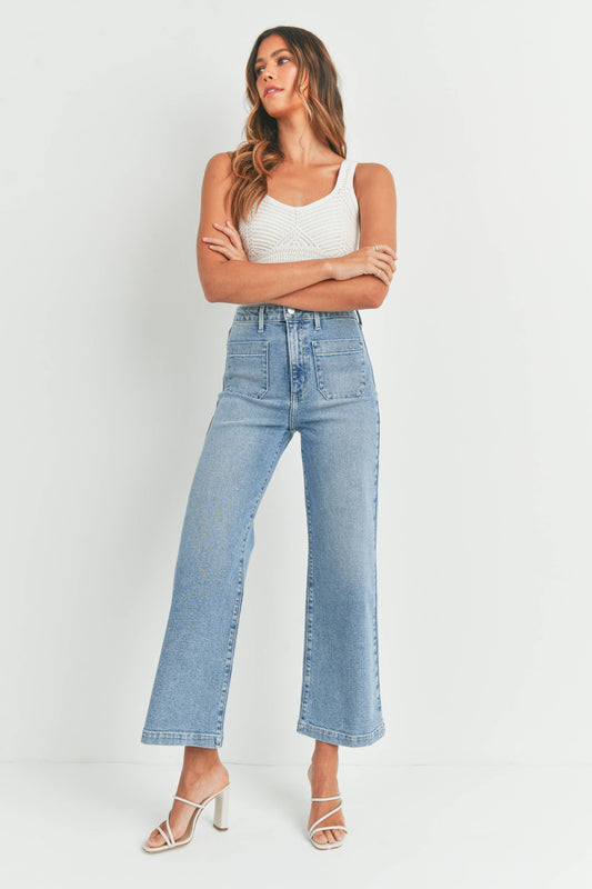 Woman wearing light blue jeans and a white top against a white background