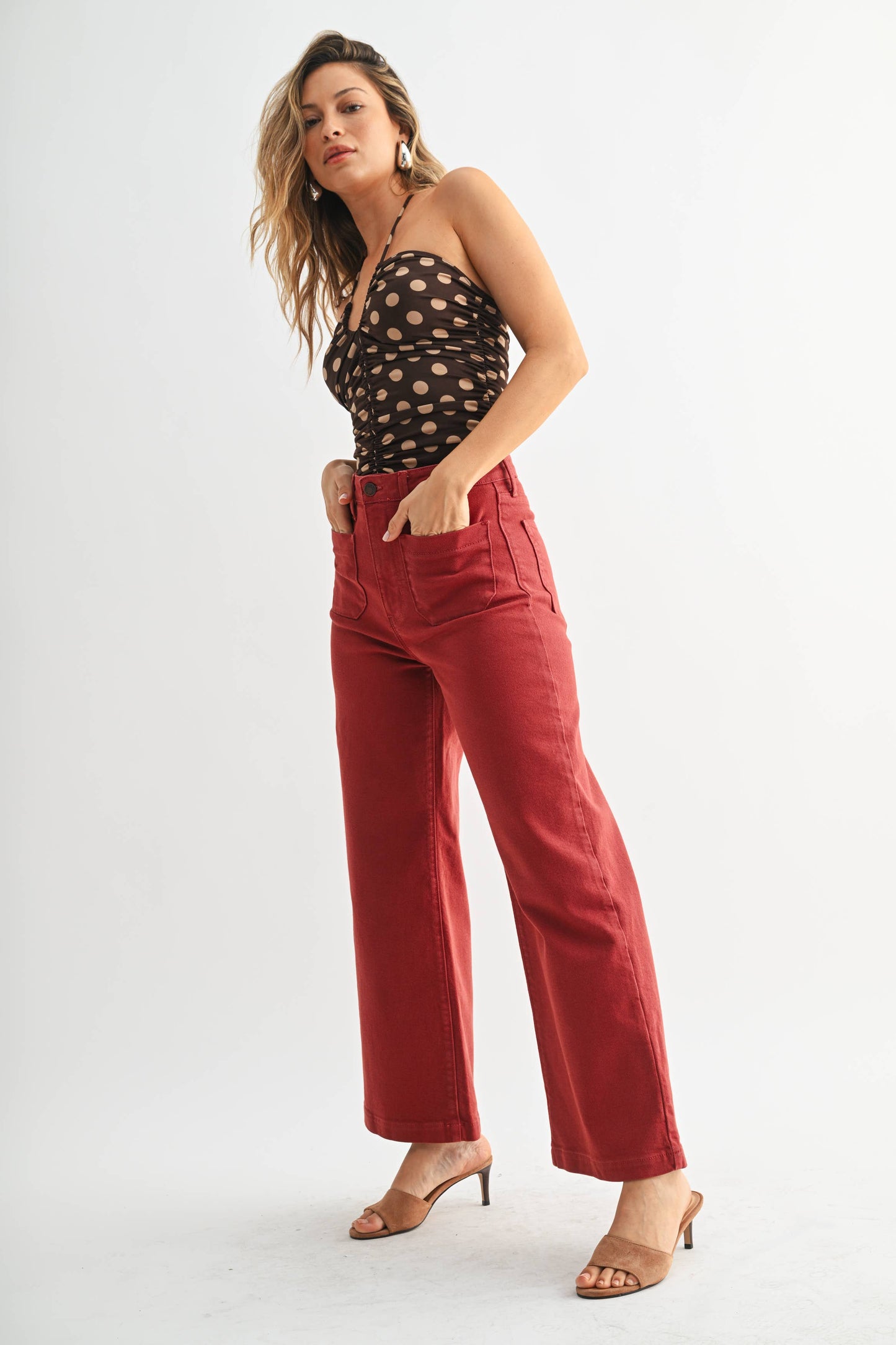 Woman wearing a black polka dot top and red pants on a white background