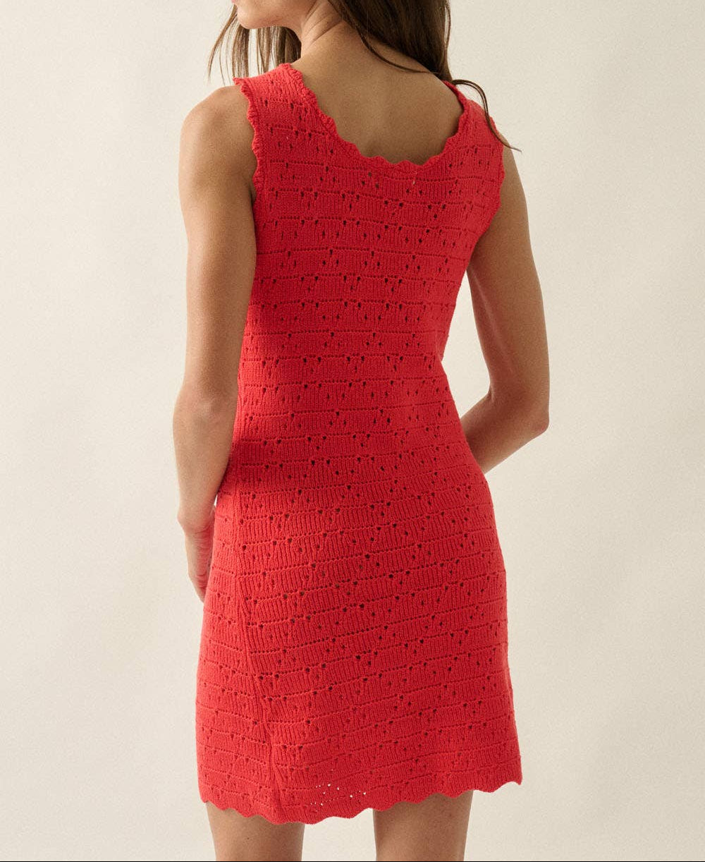Woman wearing a red crochet dress against a plain background