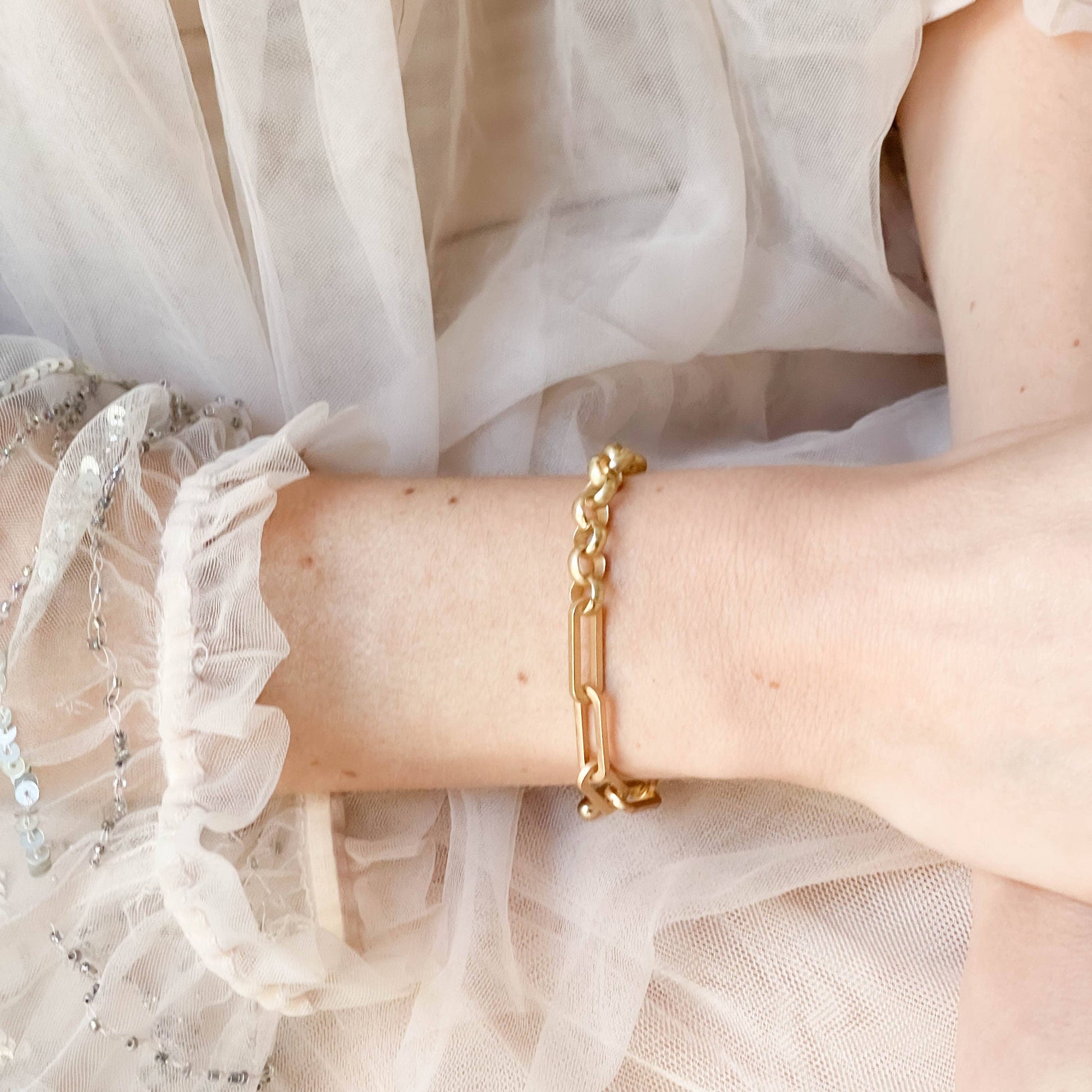 Gold bracelet on a wrist with a light background