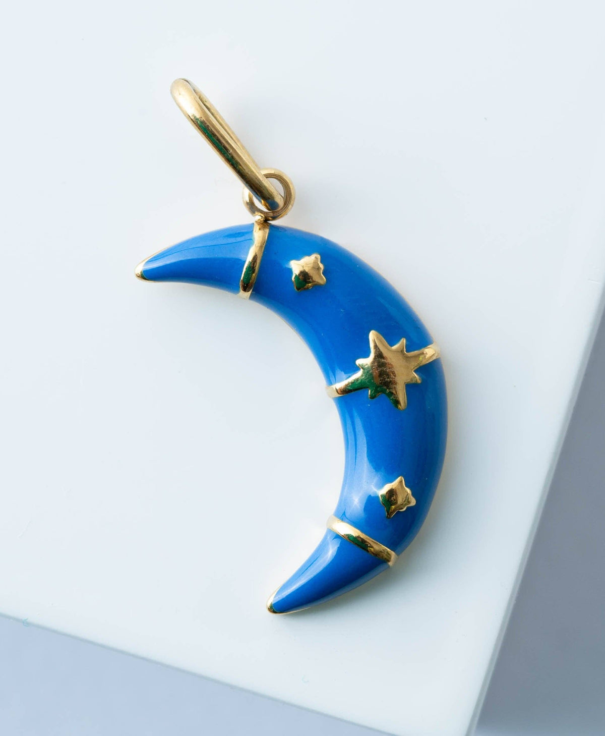 Blue crescent moon pendant with gold accents on a light gray background