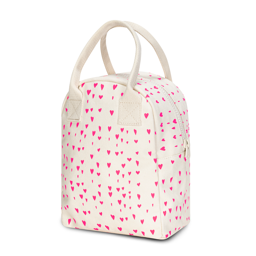 An off-white canvas lunch bag with a repeating pattern of small pink hearts, featuring dual top handles and a zippered closure, shown on a plain white background.