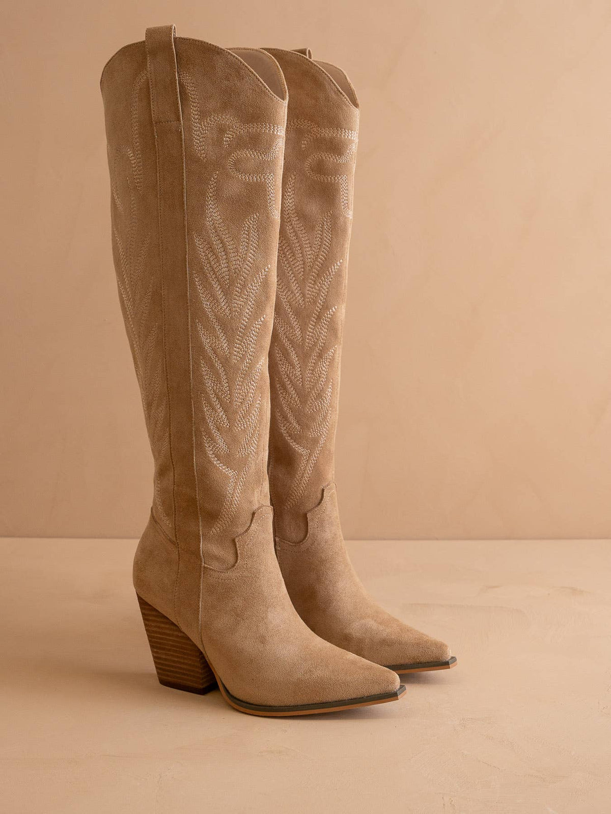 Pair of beige knee-high boots on a beige background