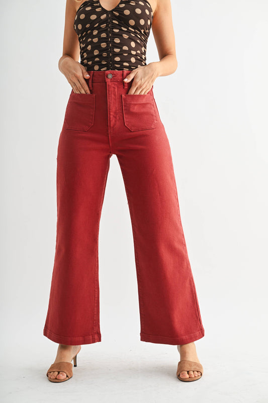 Person wearing red wide-leg jeans and a patterned top on a white background
