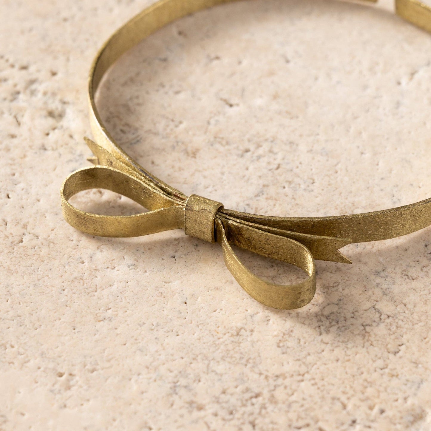 Brass headband with a bow on a textured beige surface