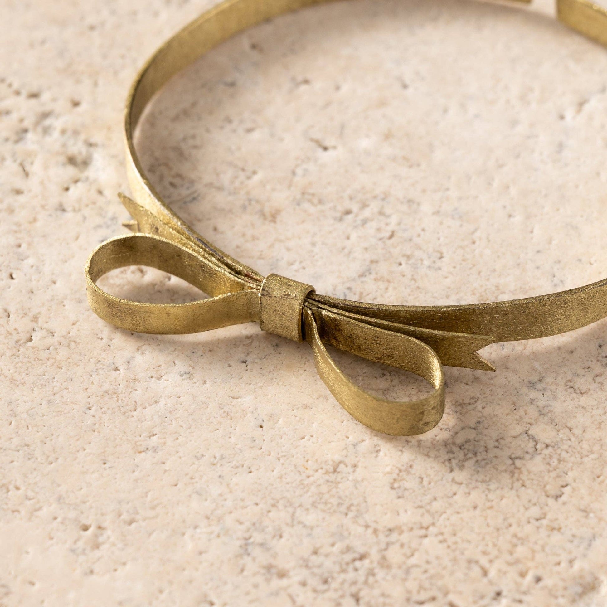 Brass headband with a bow on a textured beige surface