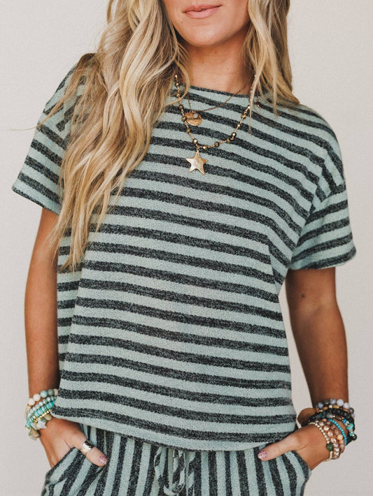 Woman wearing a green and gray striped shirt with a neutral background