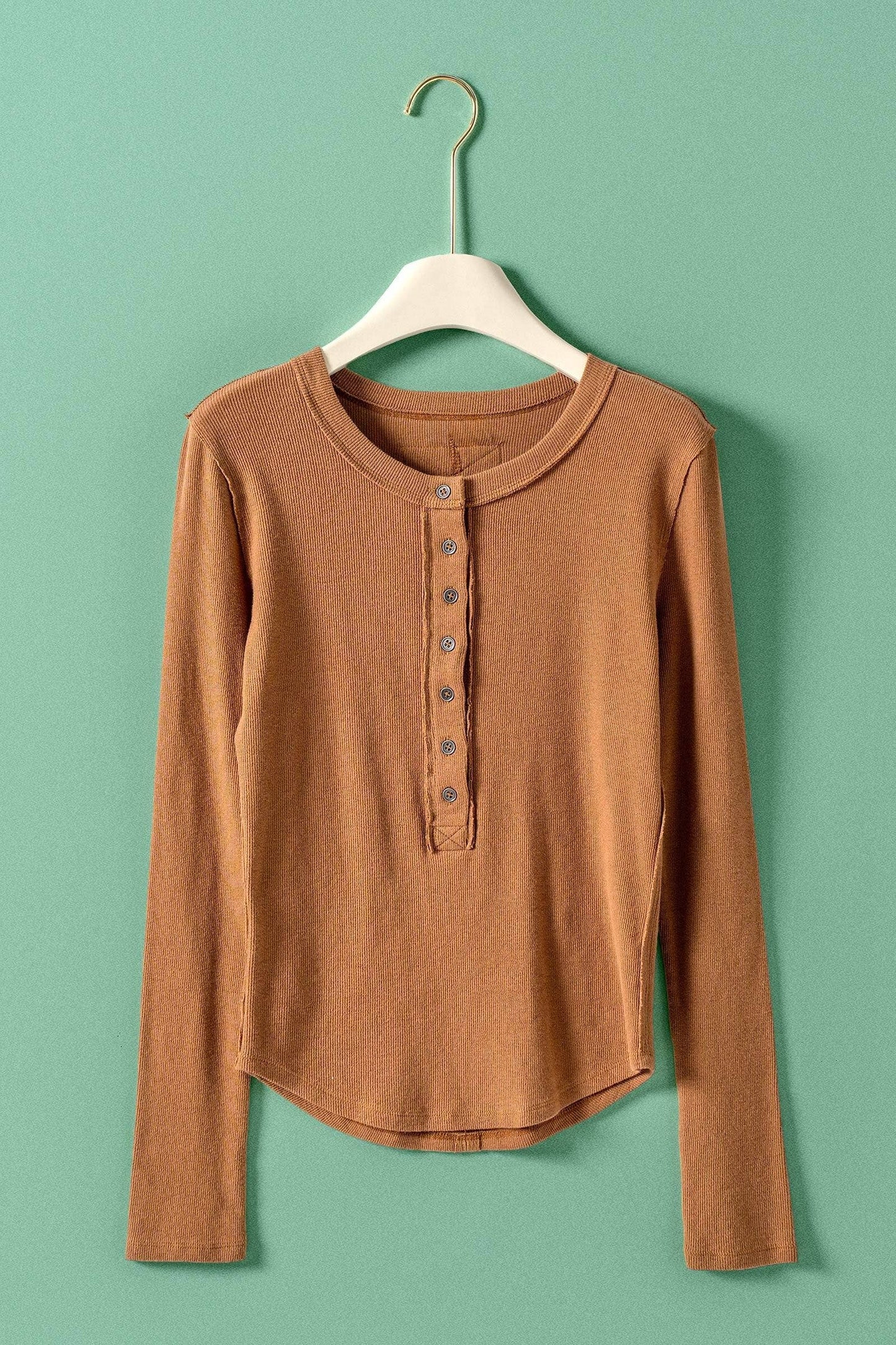 Brown long-sleeve shirt on a hanger against a green background