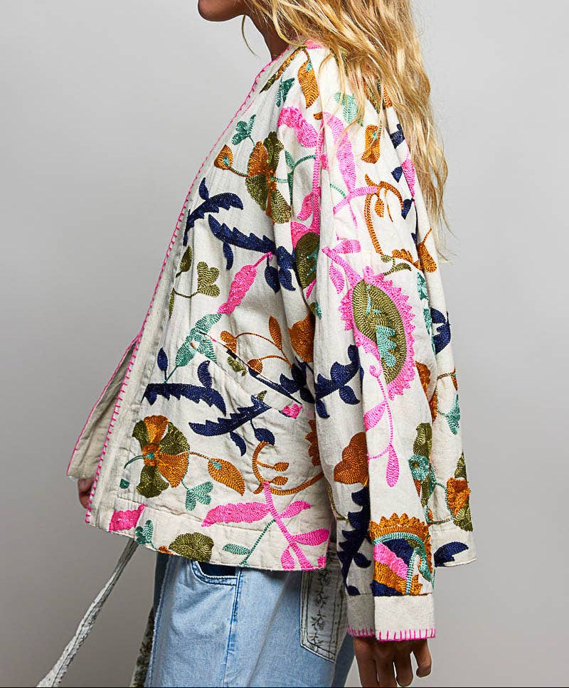 Woman wearing a colorful floral-patterned jacket on a gray background