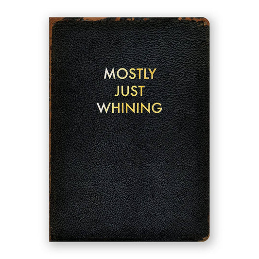 Black leather notebook with gold text 'MOSTLY JUST WHINING' on a white background