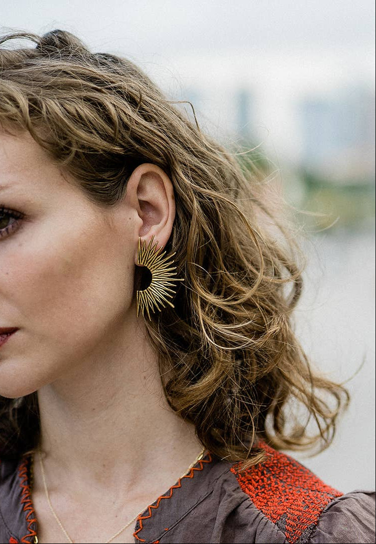 Woman with curly hair wearing a decorative earring outdoors