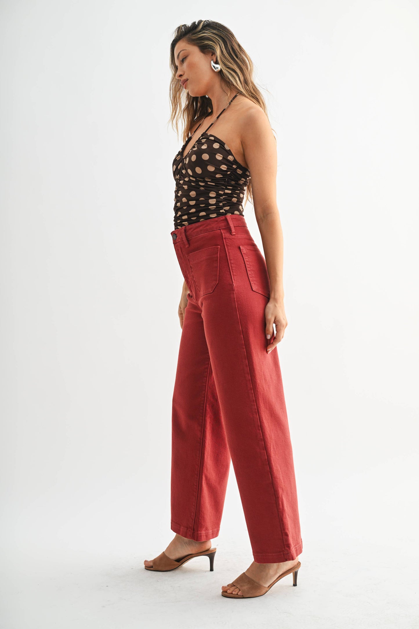 Woman wearing a black polka dot top and red pants on a white background