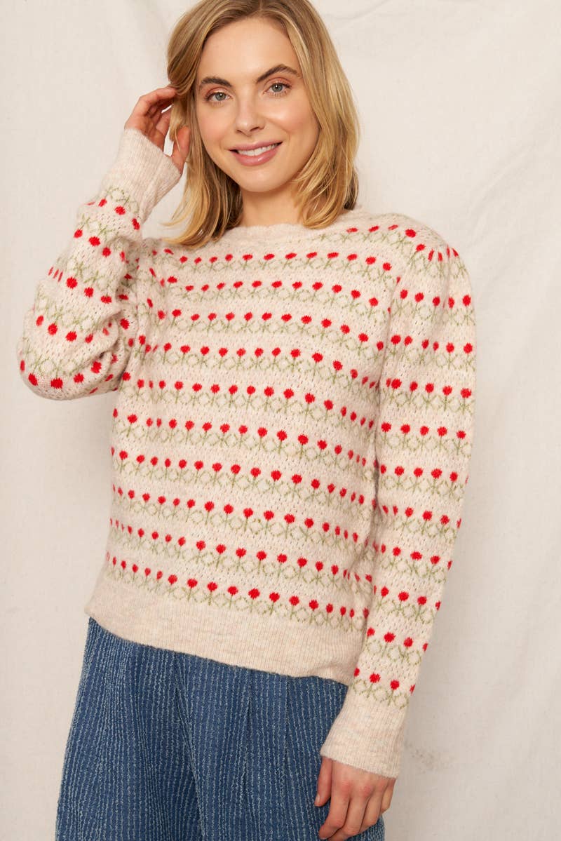 Woman wearing a patterned sweater with red and beige design against a plain background