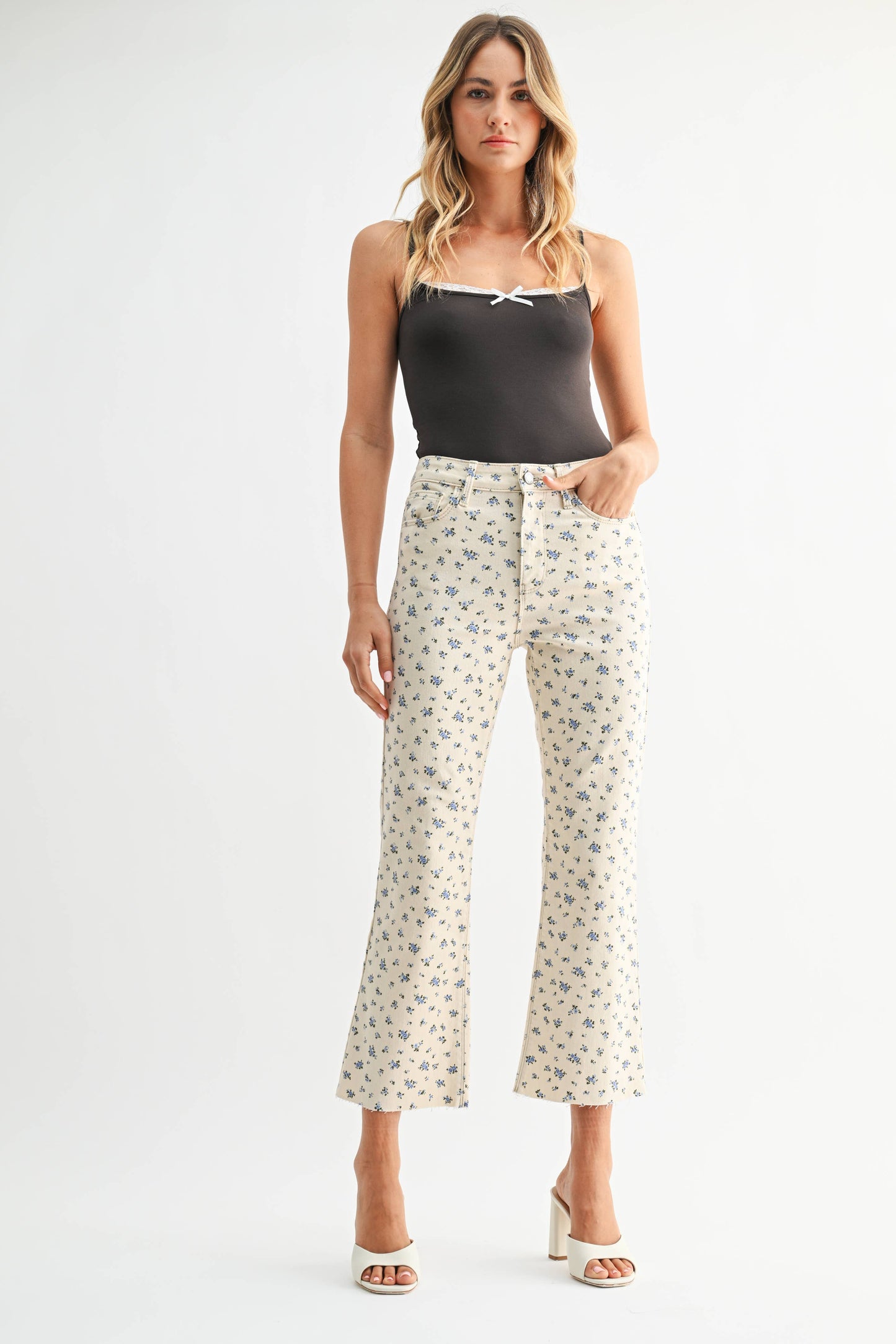Woman wearing a black tank top and patterned pants on a white background