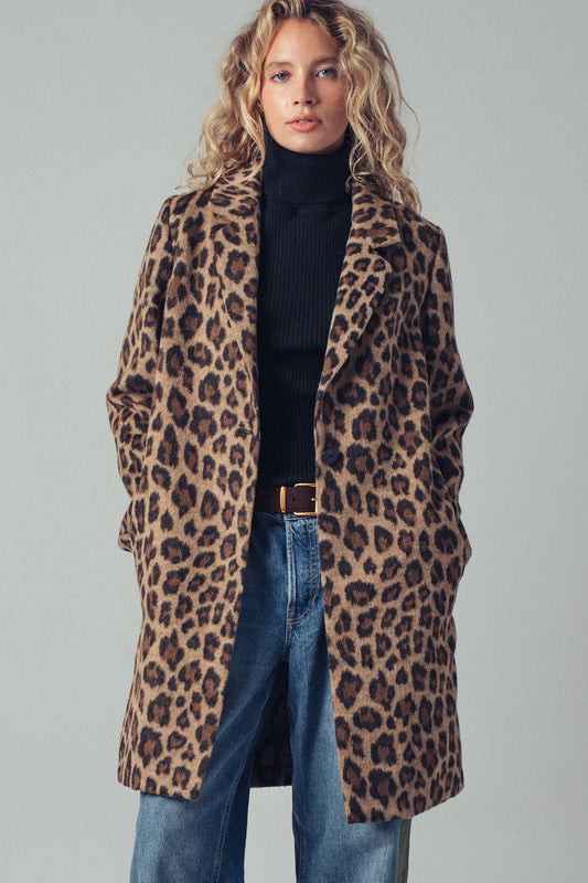 Person wearing a leopard print coat with a plain background
