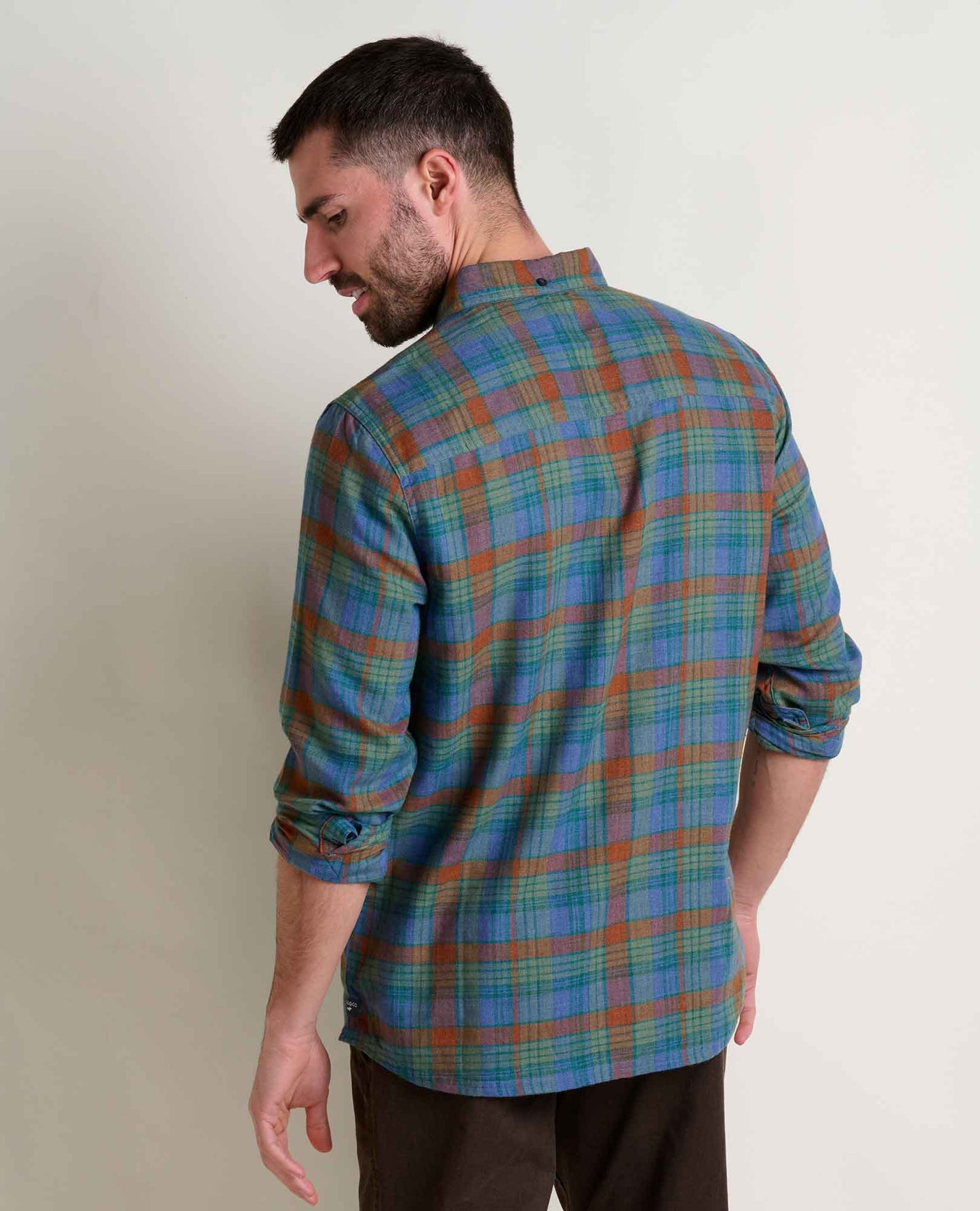 Man wearing a blue and green plaid shirt against a plain background