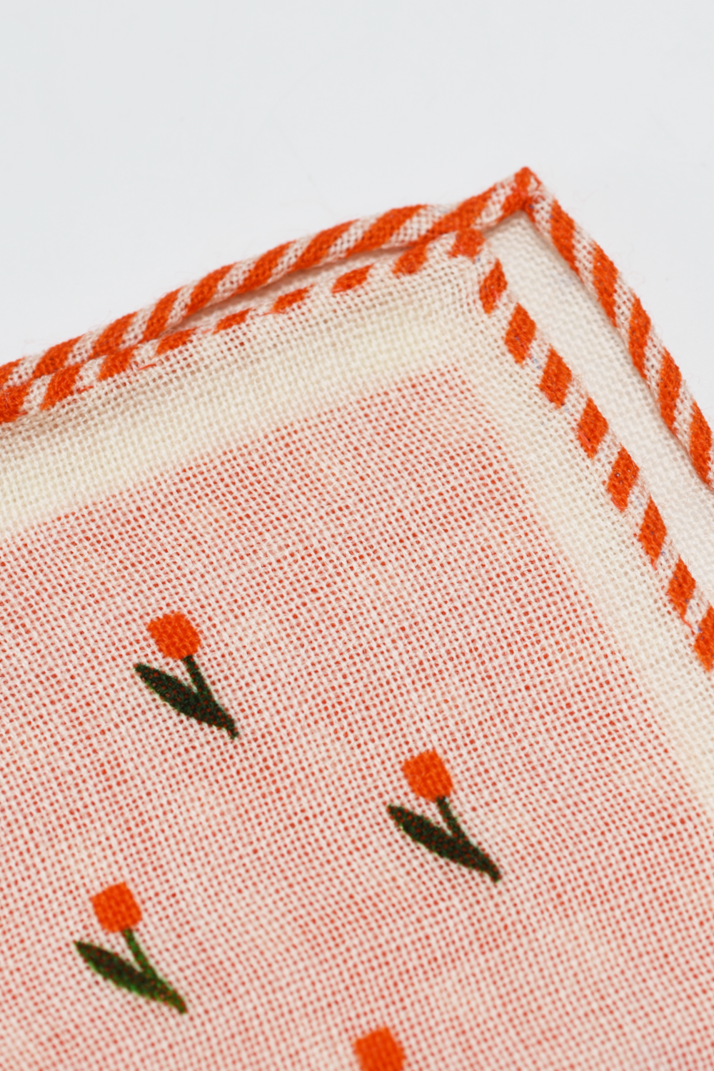 Textile with orange floral patterns and red stitching on a white background
