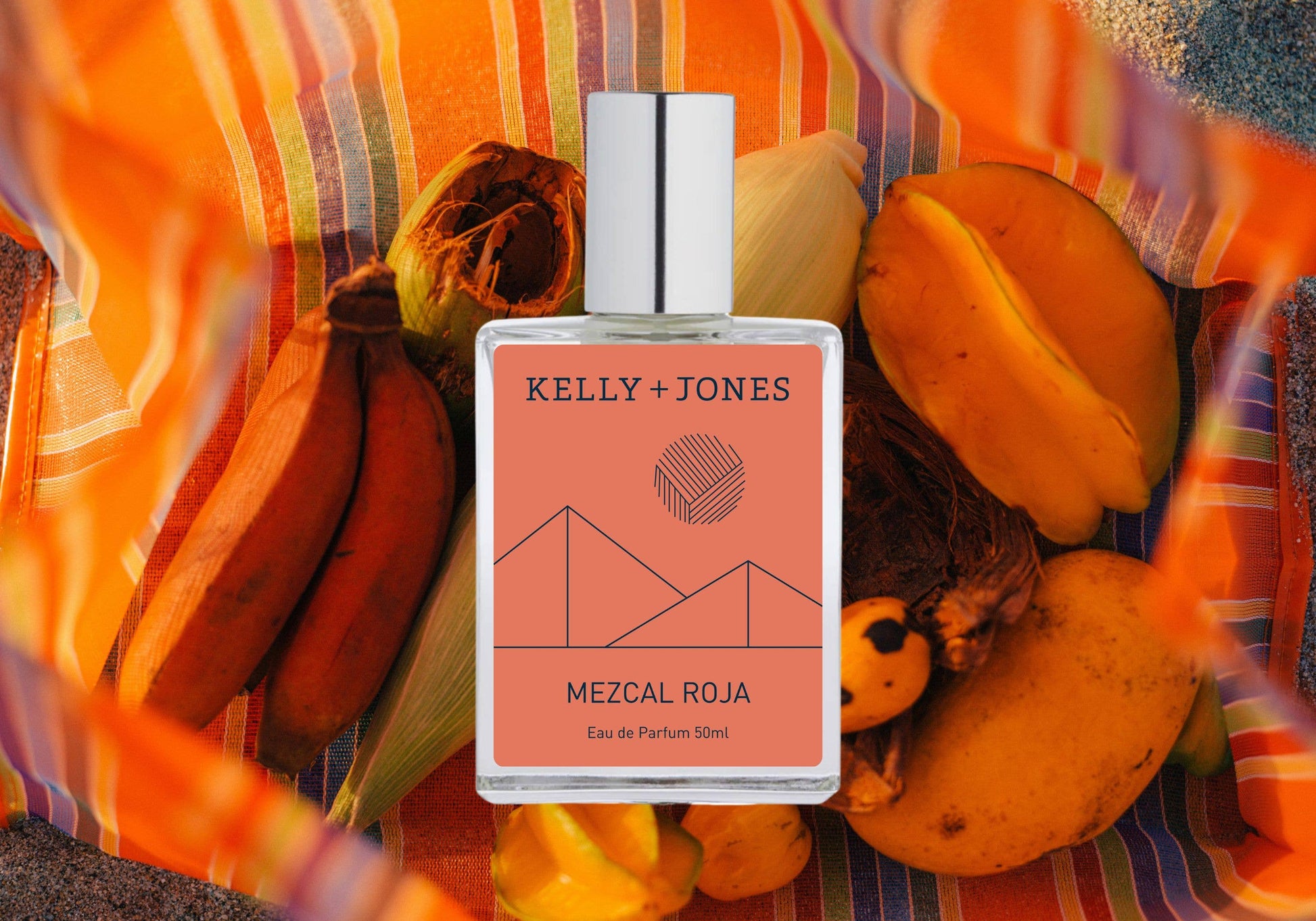 Kelly + Jones Mezcal Roja perfume bottle on a colorful background with fruits