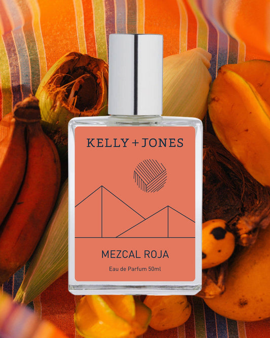 Kelly + Jones Mezcal Roja perfume bottle on a colorful background with fruits