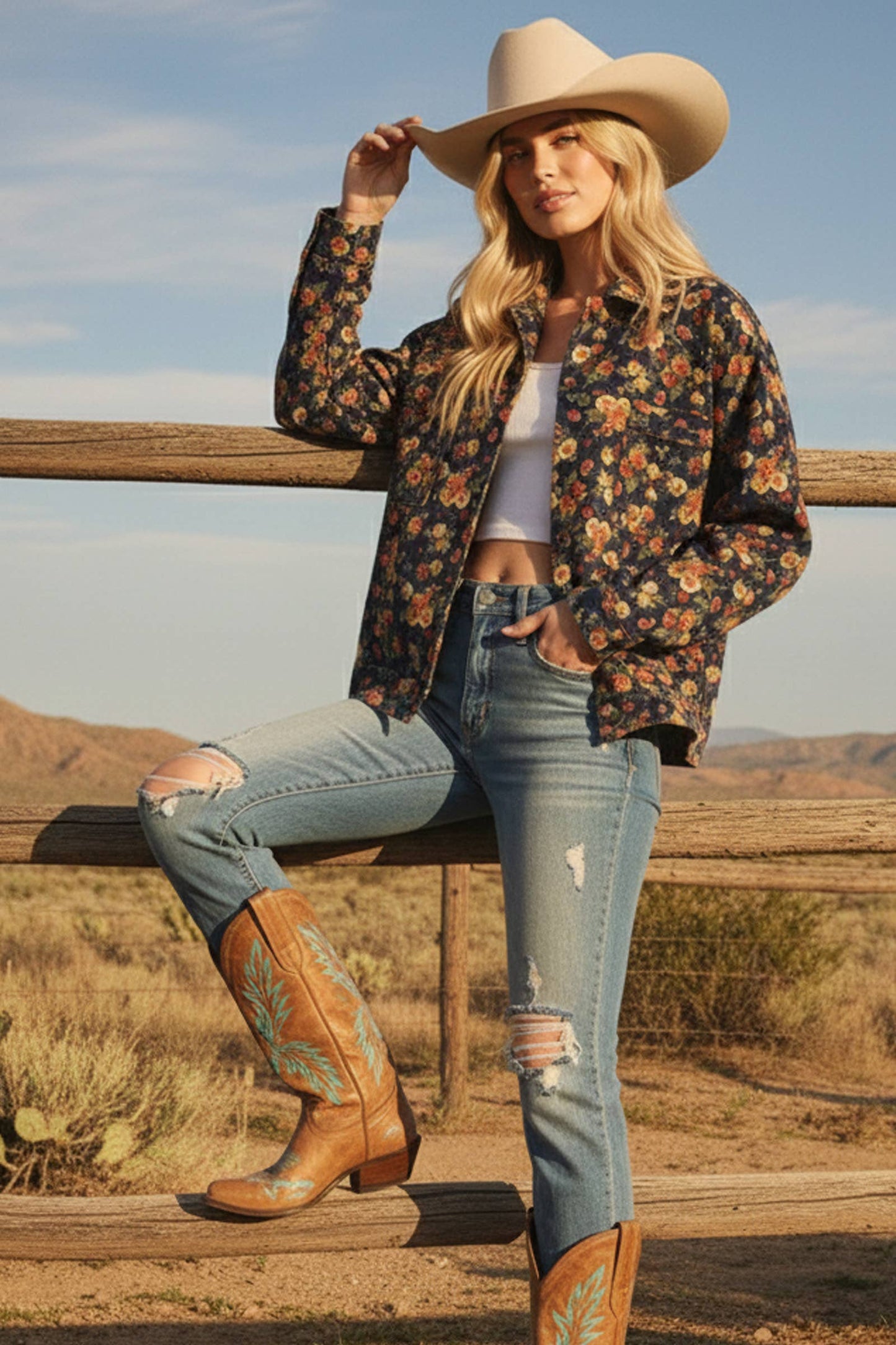 Woman in cowboy hat and boots sitting on a wooden fence with a desert landscape in the background