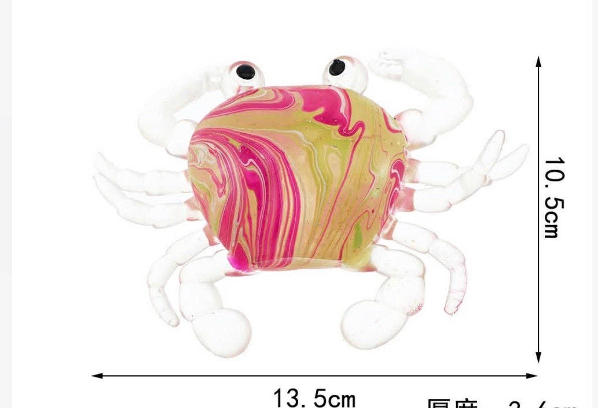 A marbled glass crab figurine with pink, yellow, and green swirls on its shell, white legs and claws, and black eyes, shown with dimension arrows and text indicating 13.5 cm width, 10.