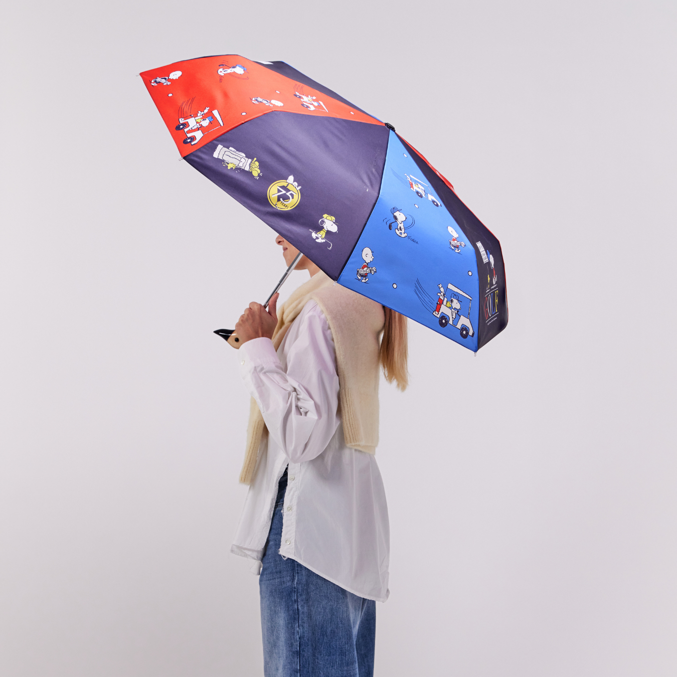 Person holding a colorful umbrella with cartoon characters on a plain background
