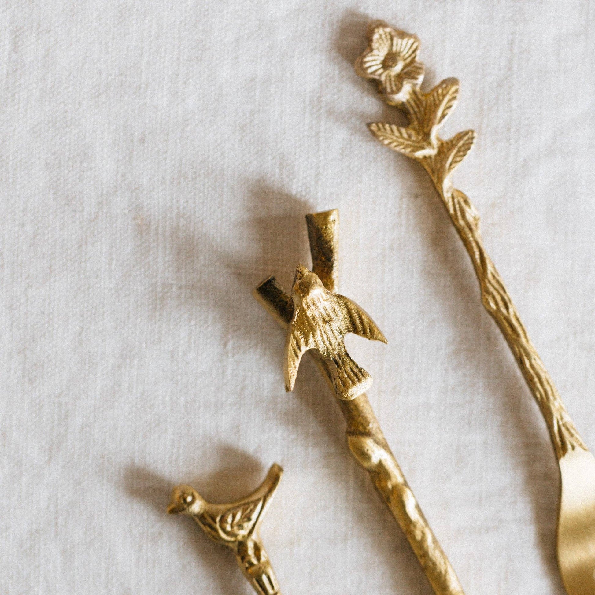 Gold bird and branch decorative items on a light background