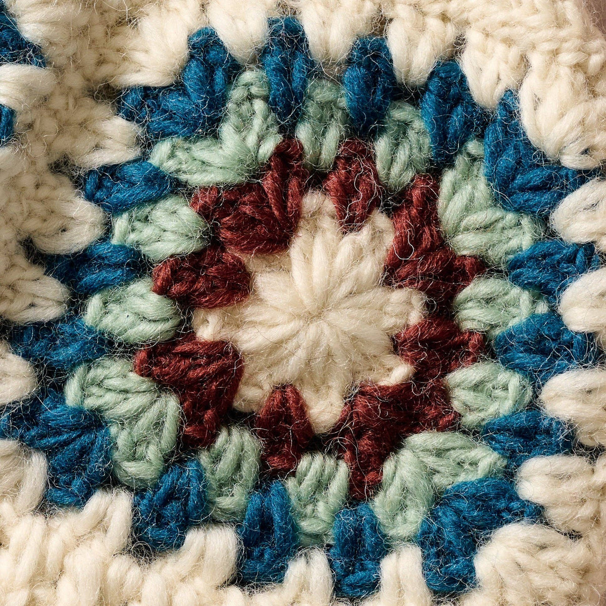 Close-up of a crocheted blanket with a circular pattern in blue, green, and red.