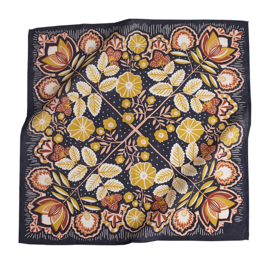 A square silk scarf with a symmetrical floral block-print pattern in yellow, brown, and white on a dark navy blue background, shown floating with soft folds.