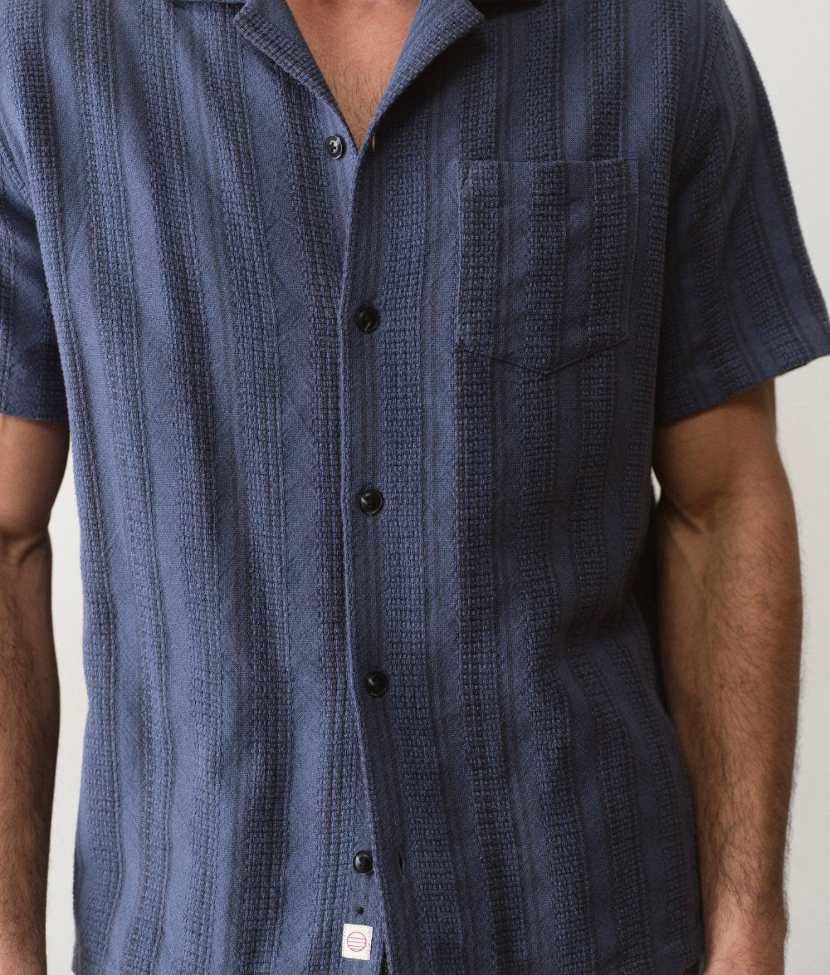 Navy blue patterned short-sleeve shirt worn by a person on a neutral background
