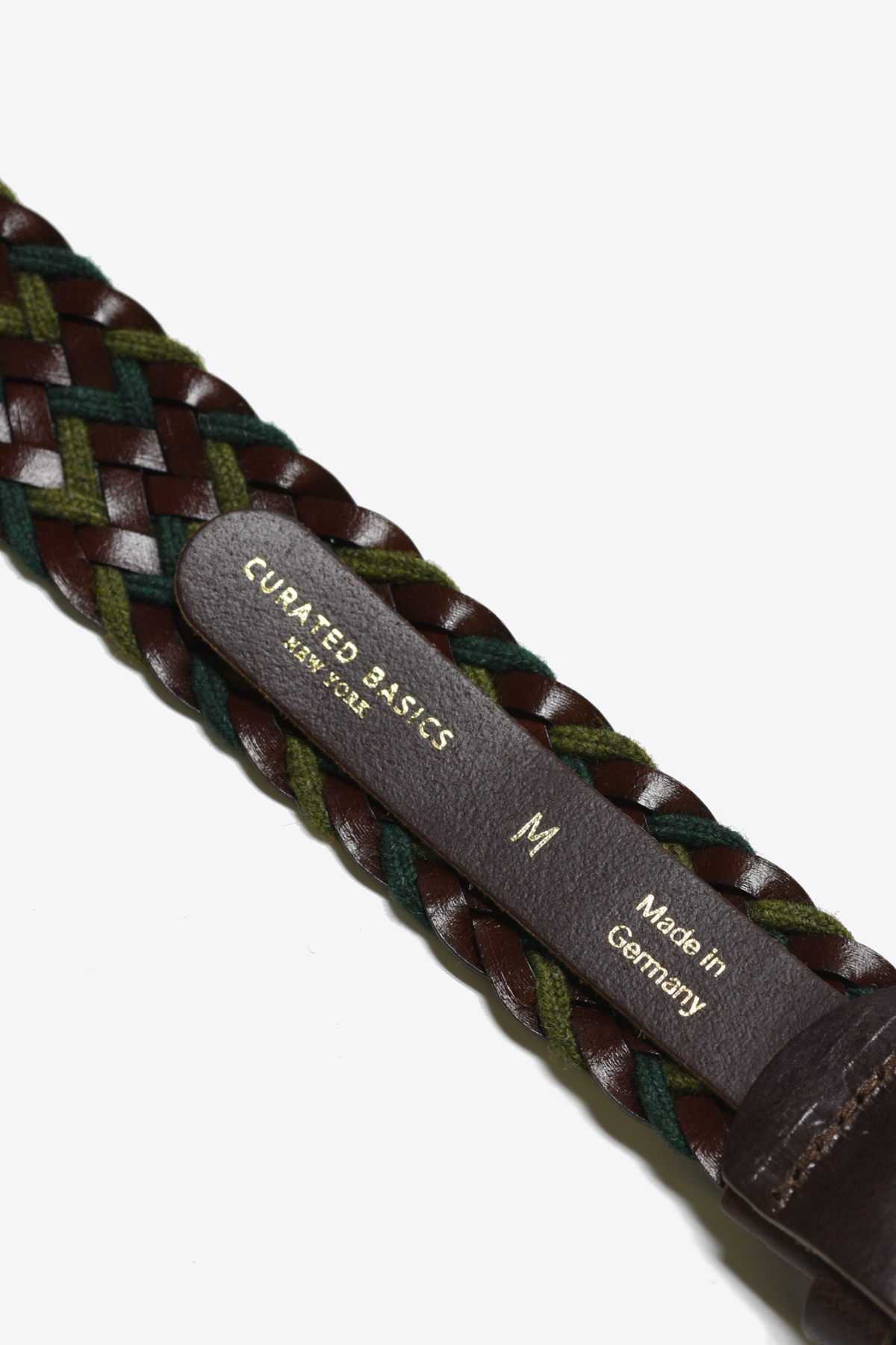 Woven belt with leather strap and 'Cuarto Basics' branding on a white background