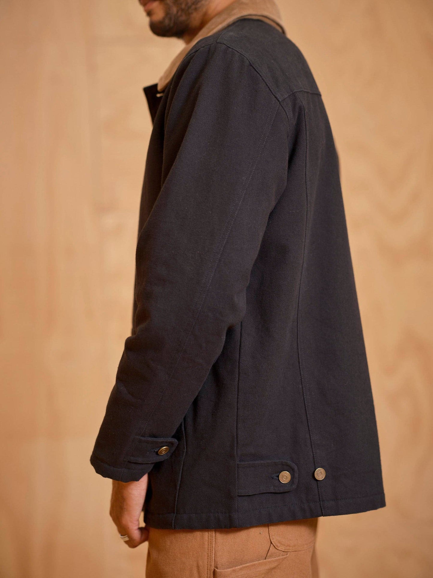 Person wearing a dark jacket against a beige background