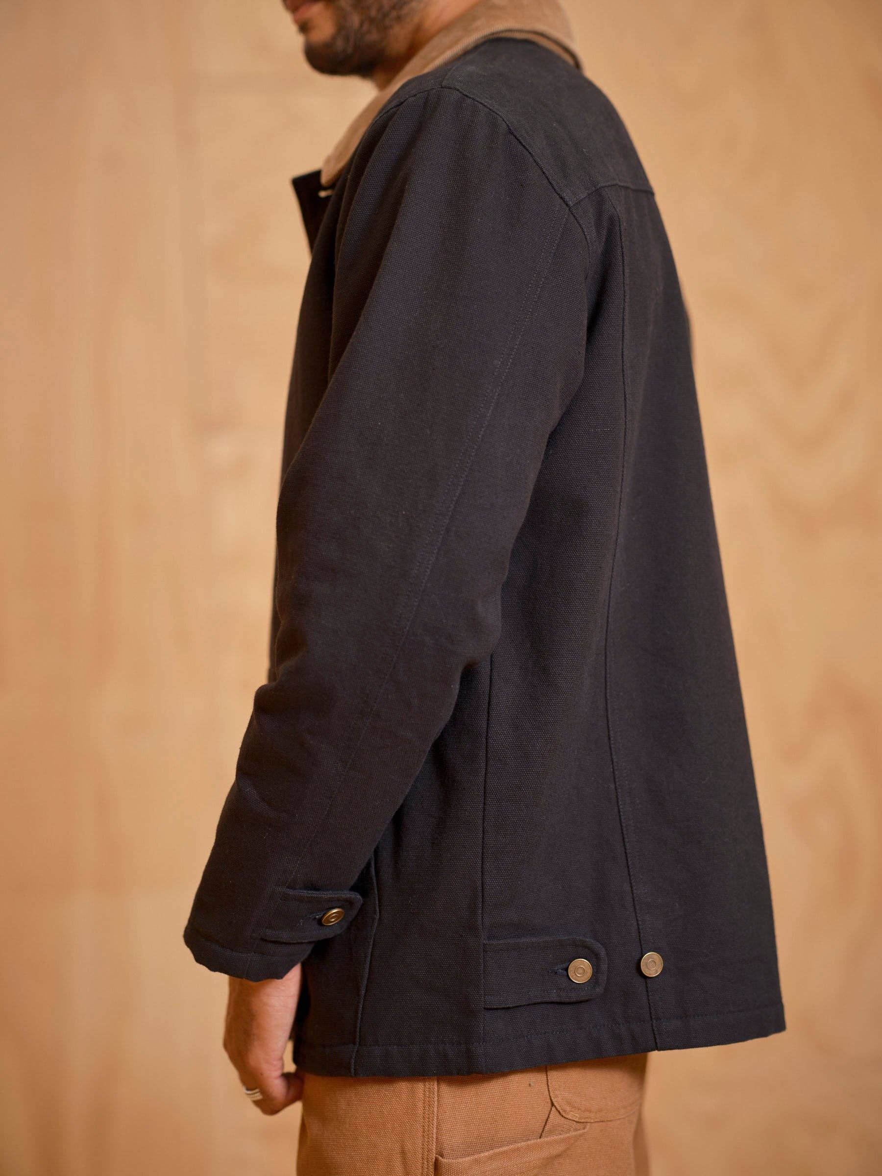 Person wearing a dark jacket against a beige background
