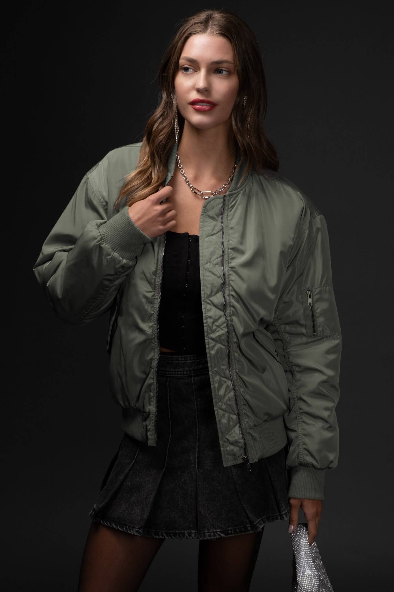 Woman wearing a green bomber jacket against a black background