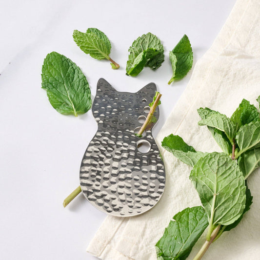 Cat-shaped metal tray with mint leaves on a white background